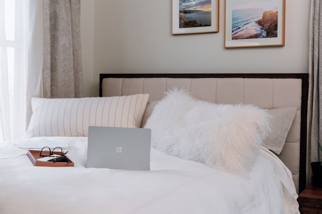 silver microsoft surface laptop on white bed