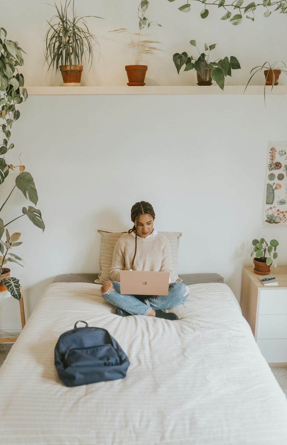 woman in beige long sleeve shirt sitting on bed using Microsoft Surface Laptop 3 in Sandstone