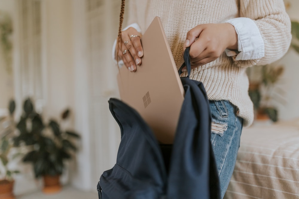 woman in blue denim jeans holding sandstone surface laptop 