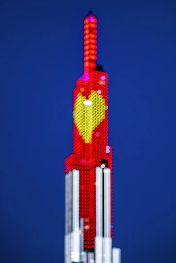 A sleek modern financial district building glowing with red heart tones at dusk.