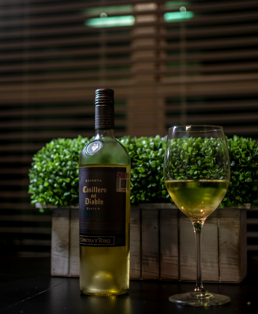 green wine bottle beside clear wine glass