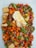 A colorful mix of cut vegetables and tofu is presented on a plate, featuring bright orange carrots, green beans, and red peppers. There is a piece of fried egg on top, adding a contrasting texture and color.