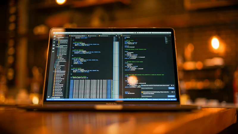 Laptop showing code on a wooden table at night