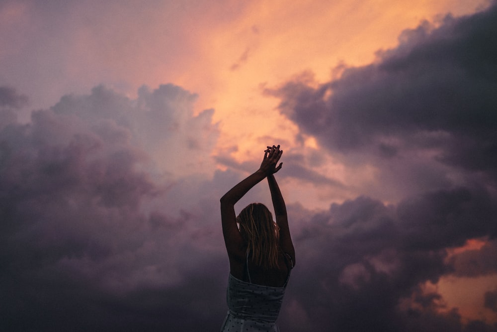 woman in black tank top and blue denim jeans raising her hands