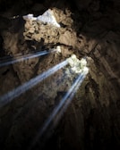 Sunlight filtering through the entrance of a vast cave in Trang An landscape complex.