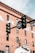 A traffic light and street signs set against the backdrop of a historic red brick building. The building has several windows and faded signage. The street sign mentions 'Denver' and another sign reads 'Do Not Enter' with exceptions for buses.