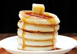 A plate of fluffy pancakes drizzled with maple syrup.