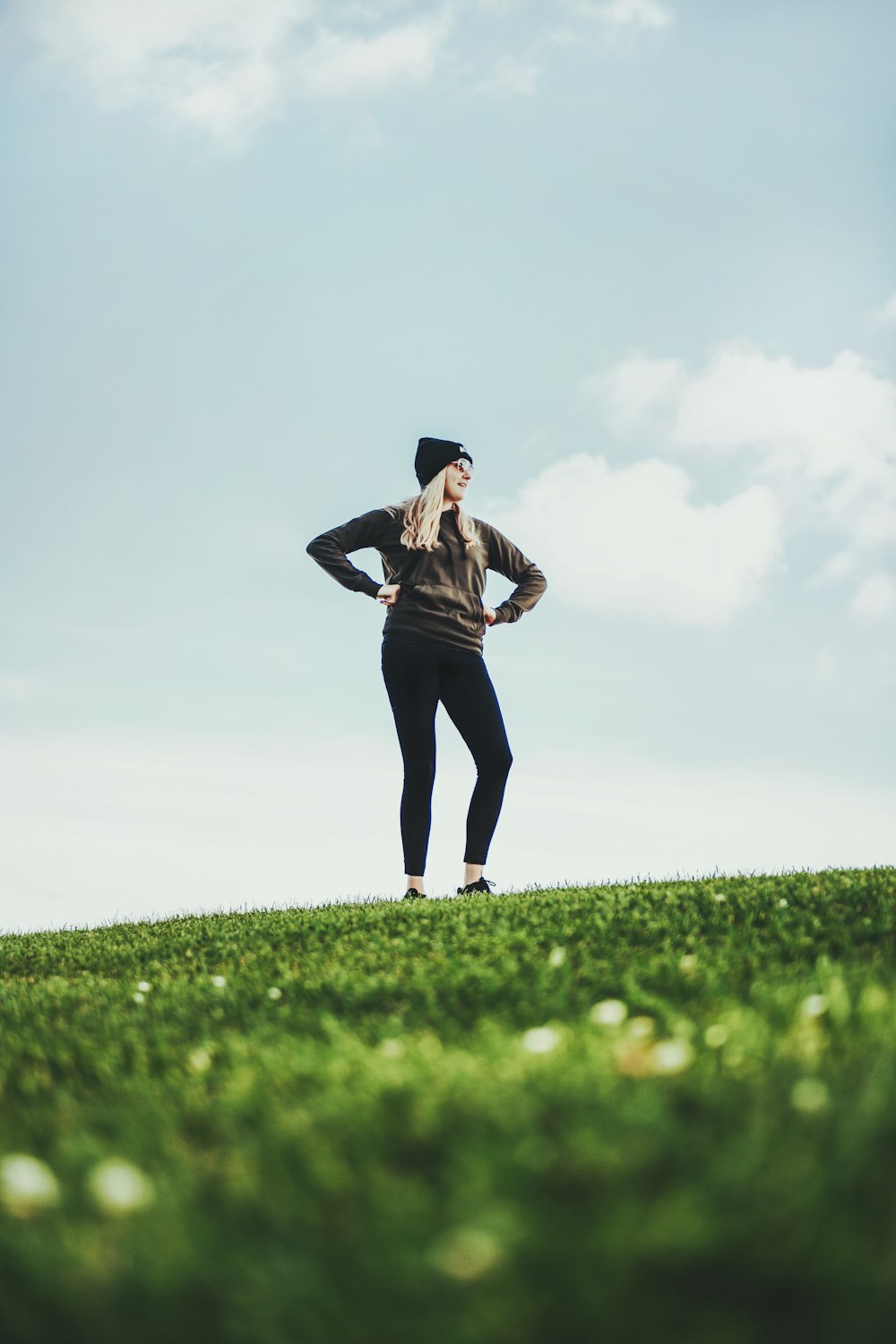 woman in black long sleeve shirt and black pants standing on green grass field during daytime