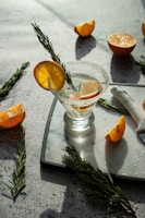 An elegant glass of natural aperitif with a slice of citrus and sprigs of fresh herbs on a light linen cloth.
