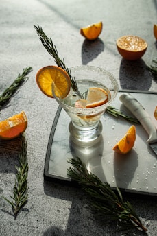 An elegant glass of natural aperitif with a slice of citrus and sprigs of fresh herbs on a light linen cloth.