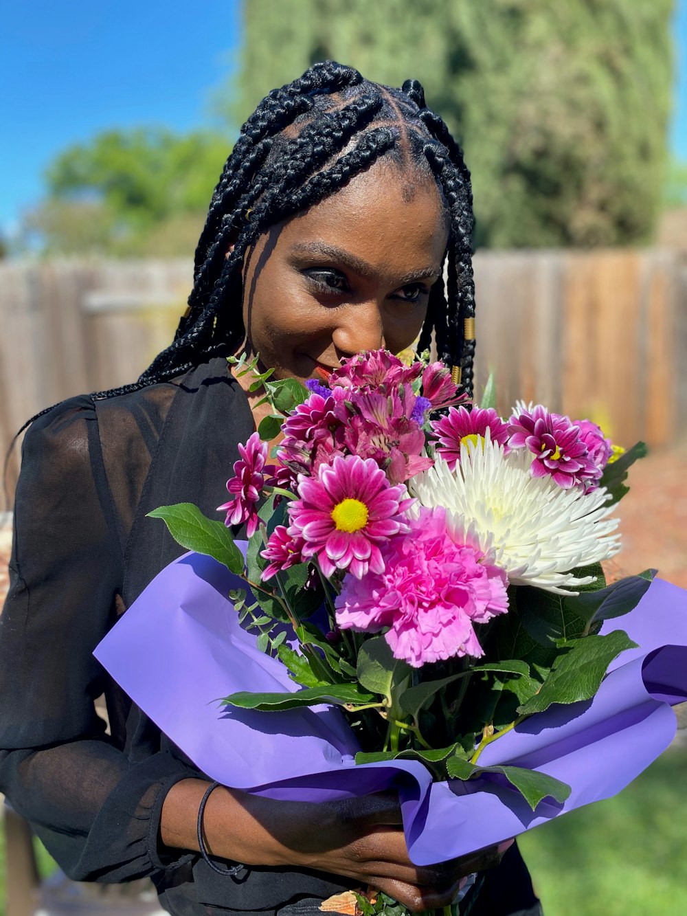 woman in black coat holding purple flower