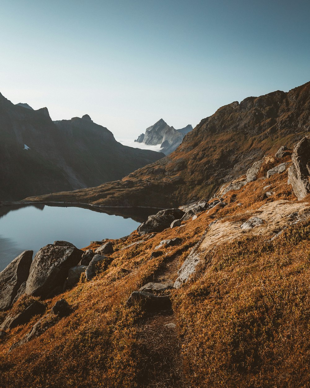 brown rocky mountain near body of water during daytime