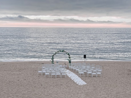 Beautiful wedding setup on a beach with elegant decorations and sunset.