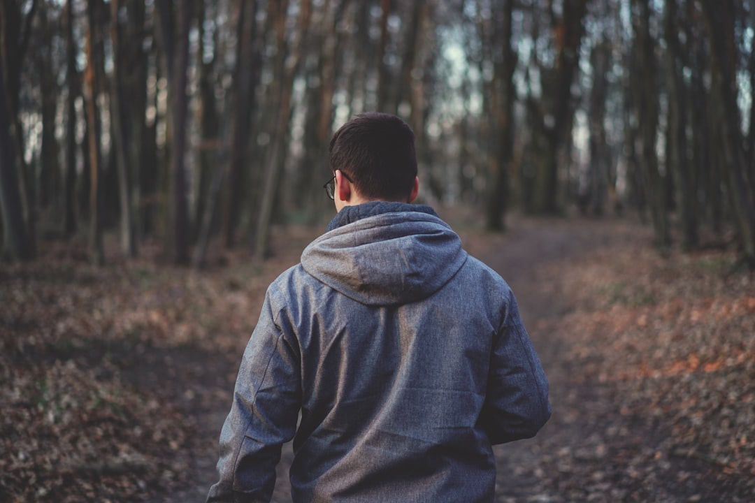 man in gray hoodie standing in forest during daytime