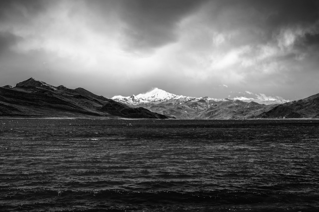 grayscale photo of mountains near body of water