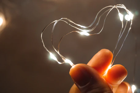 Close-up of hands gently holding a glowing heart-shaped light symbolizing hope and compassion.