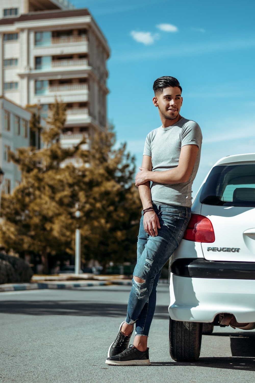 man in gray crew neck t-shirt and blue denim jeans standing on road during daytime