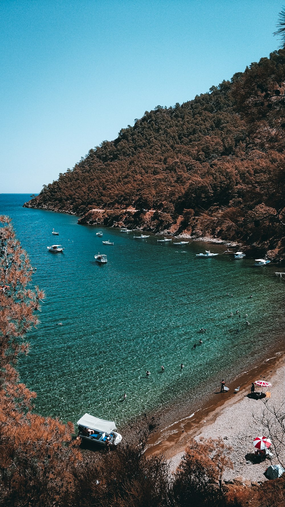 aerial view of boats on sea near brown and green mountain during daytime