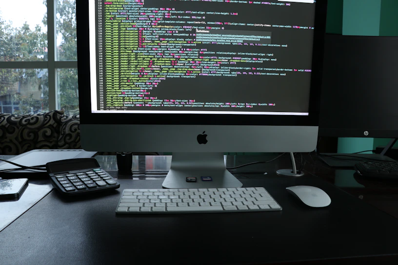 Photo of a modern office workspace with computer screens displaying coding and development software.