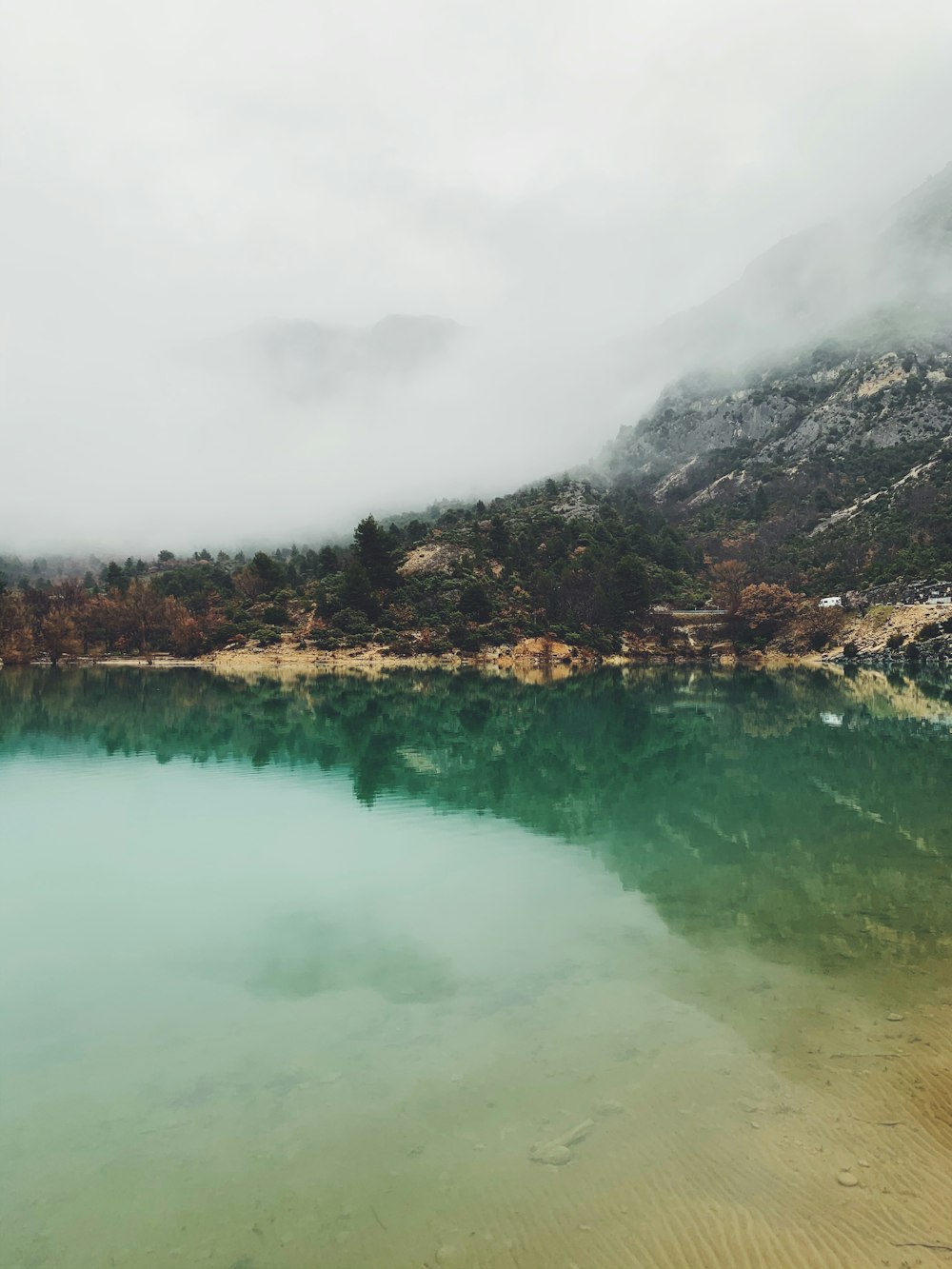 lake near mountain under cloudy sky during daytime