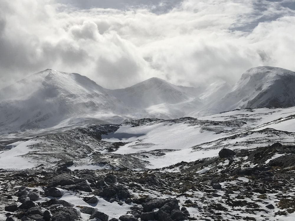 snow covered mountain under white clouds during daytime