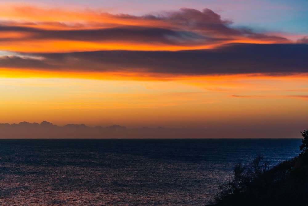 body of water under cloudy sky during sunset