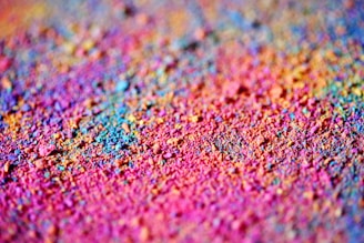 Vibrant and colorful powder scattered across a surface, creating a textured and dynamic pattern with a blend of hues.