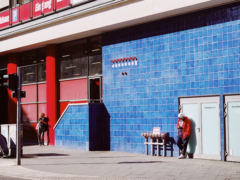 people walking on sidewalk near blue building during daytime