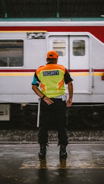 man in orange helmet and green and blue stripe polo shirt standing beside white and red