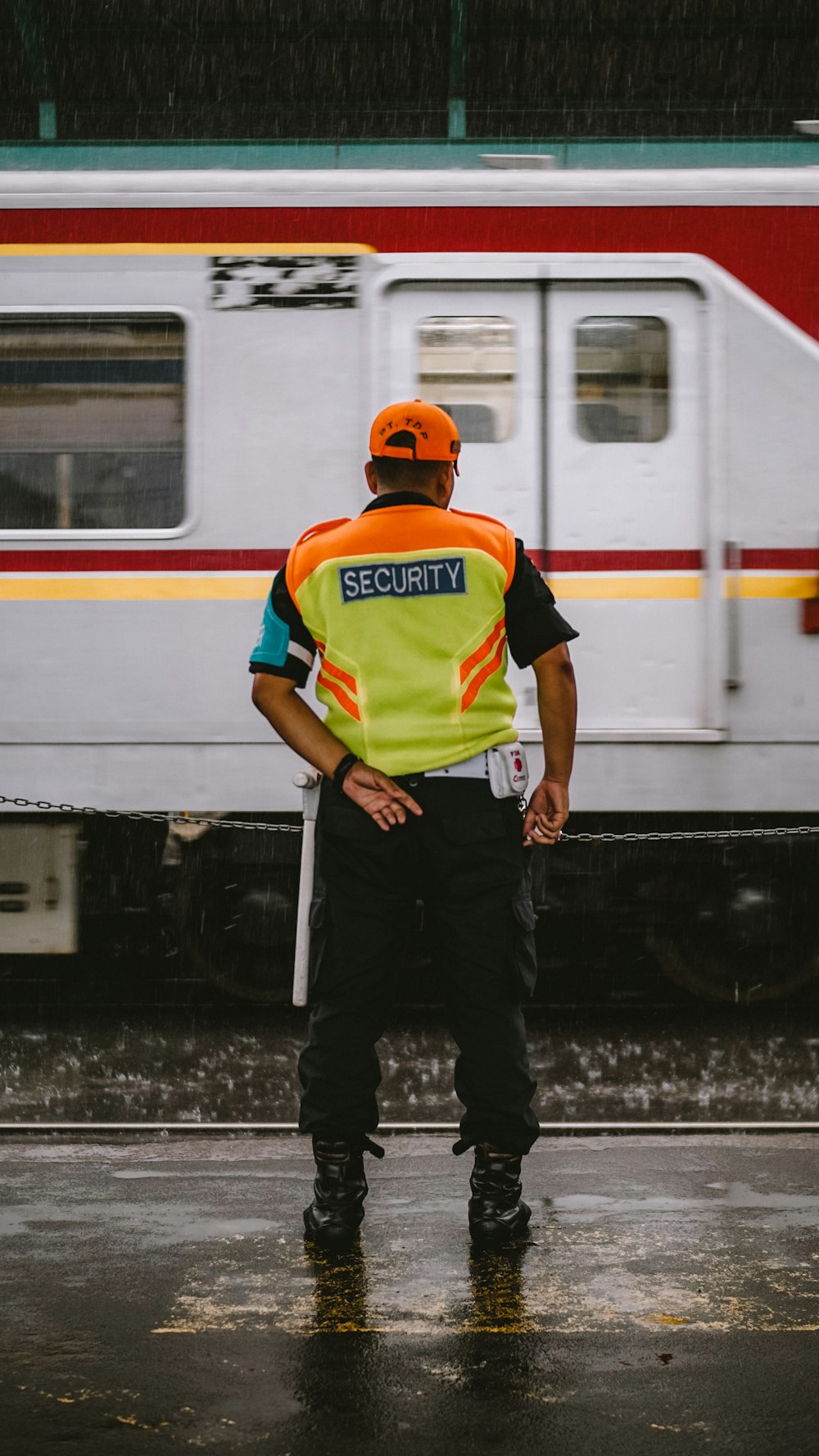 man in orange helmet and green and blue stripe polo shirt standing beside white and red