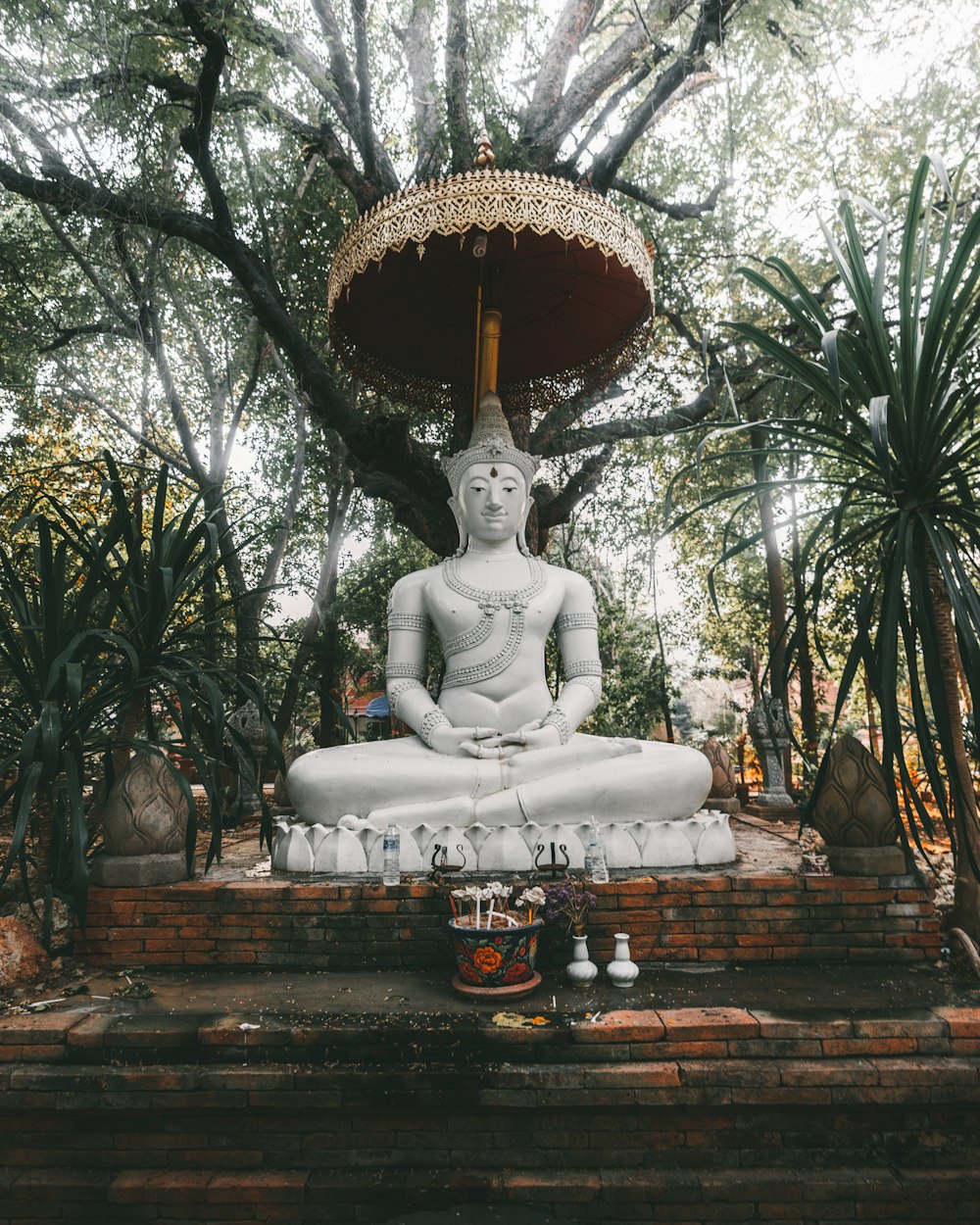 white concrete statue of a man sitting on a rock