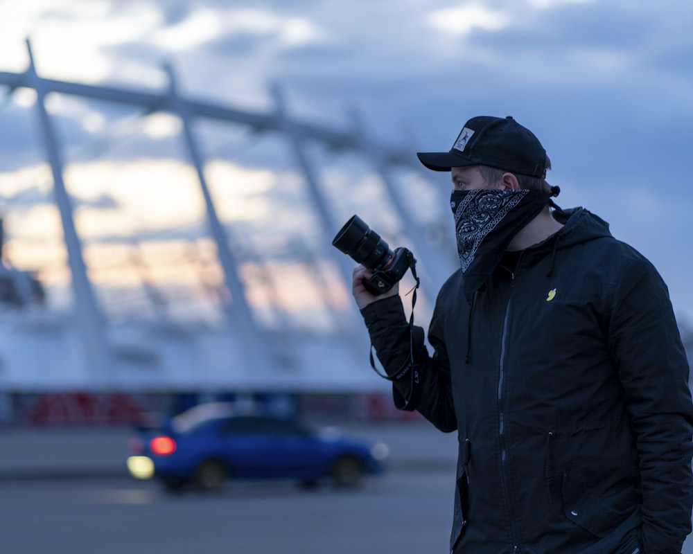 Mann in schwarzer Jacke mit schwarzer DSLR-Kamera