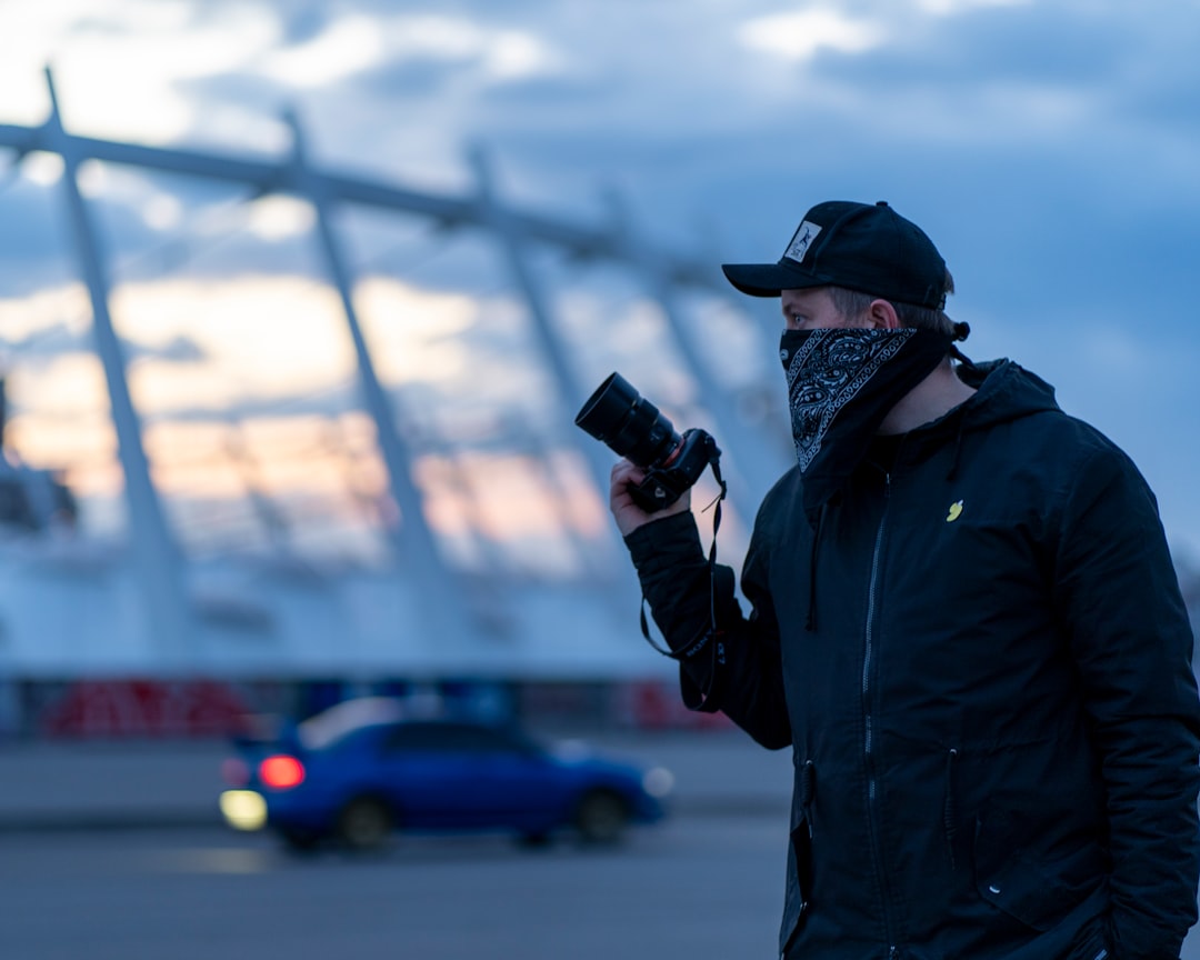 man in black jacket holding black dslr camera