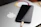 Close-up of a sleek white iPhone charger plugged in and charging a smartphone on a wooden desk.