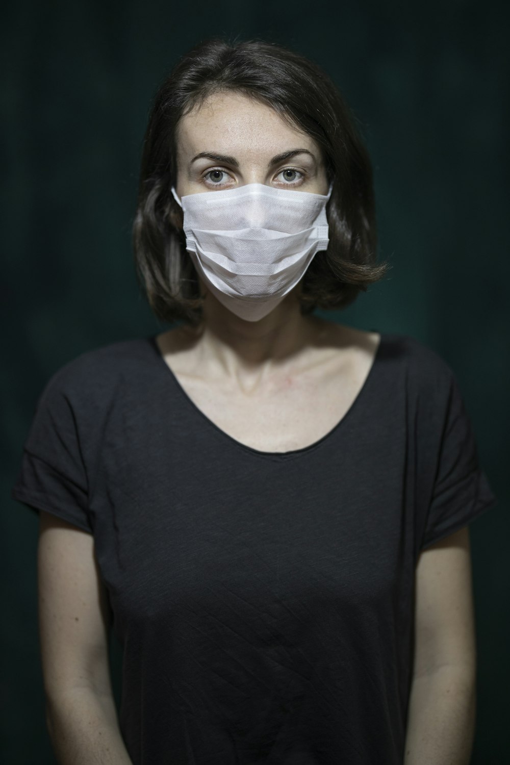 donna in camicia nera con scollo rotondo e maschera facciale bianca