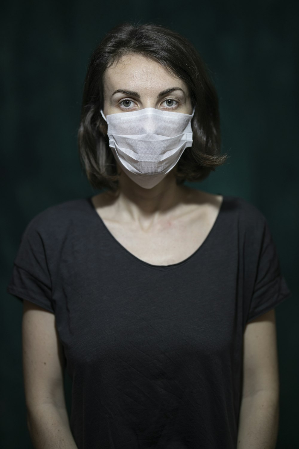 Mujer con camisa negra de cuello redondo con mascarilla blanca