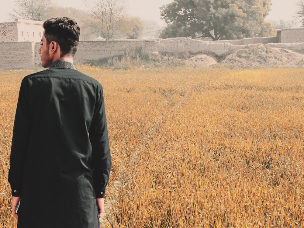 man in black suit standing on brown grass field during daytime