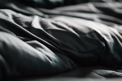 Delicate folds of charcoal-hued linen with visible texture under natural light.