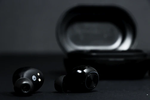 Stylish pair of black and gold wireless earbuds glowing softly against a dark background
