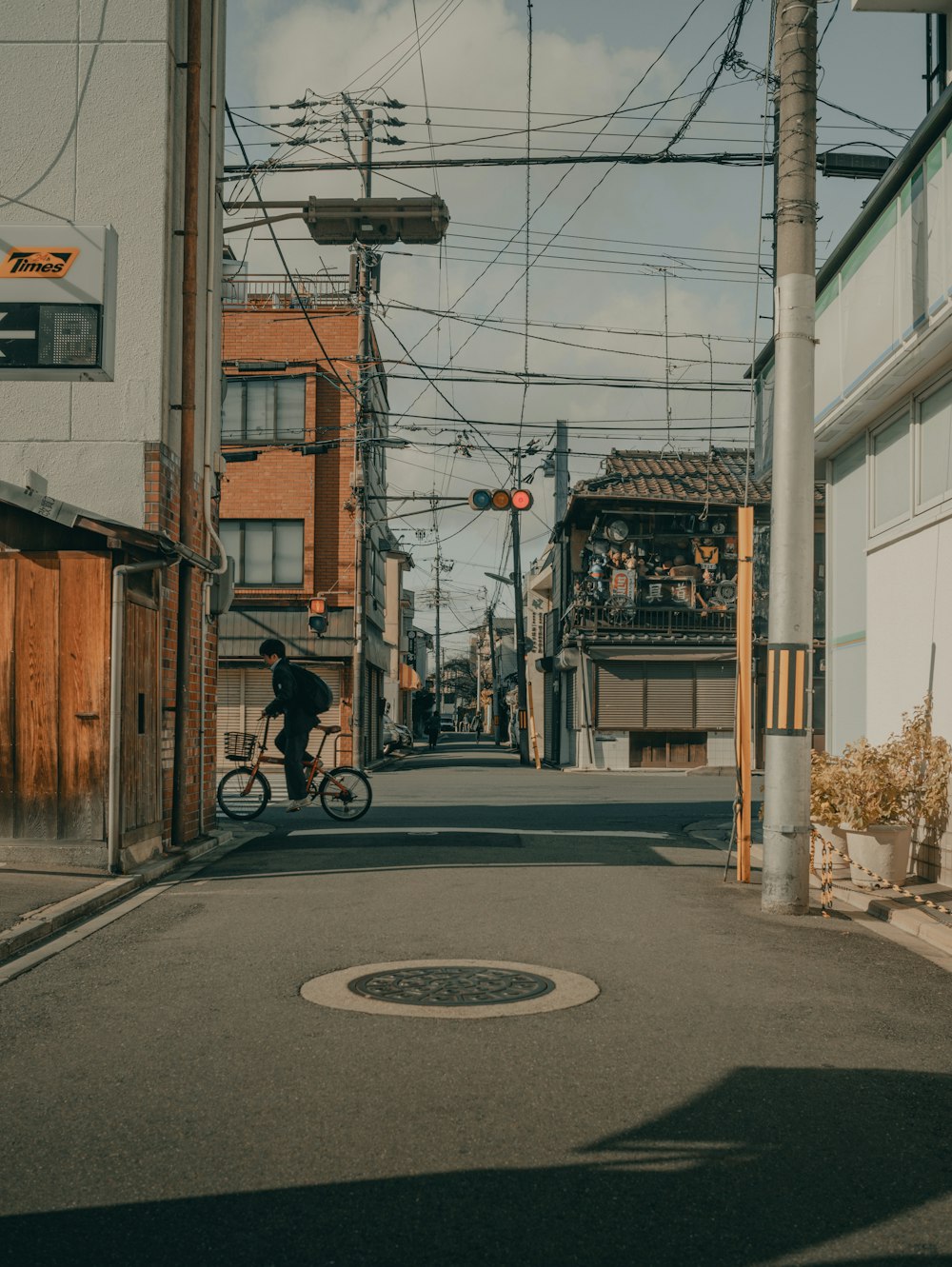 昼間、道路を自転車で走る黒いジャケットの男