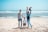 A happy family playing on a sunny beach with palm trees in the background.