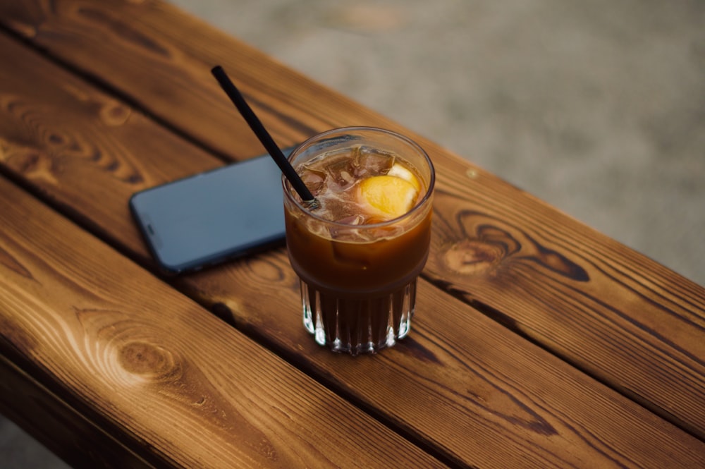 clear drinking glass with brown liquid on brown wooden table