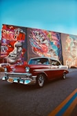 red classic car parked beside wall with graffiti