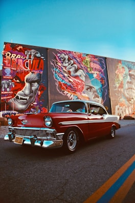 red classic car parked beside wall with graffiti
