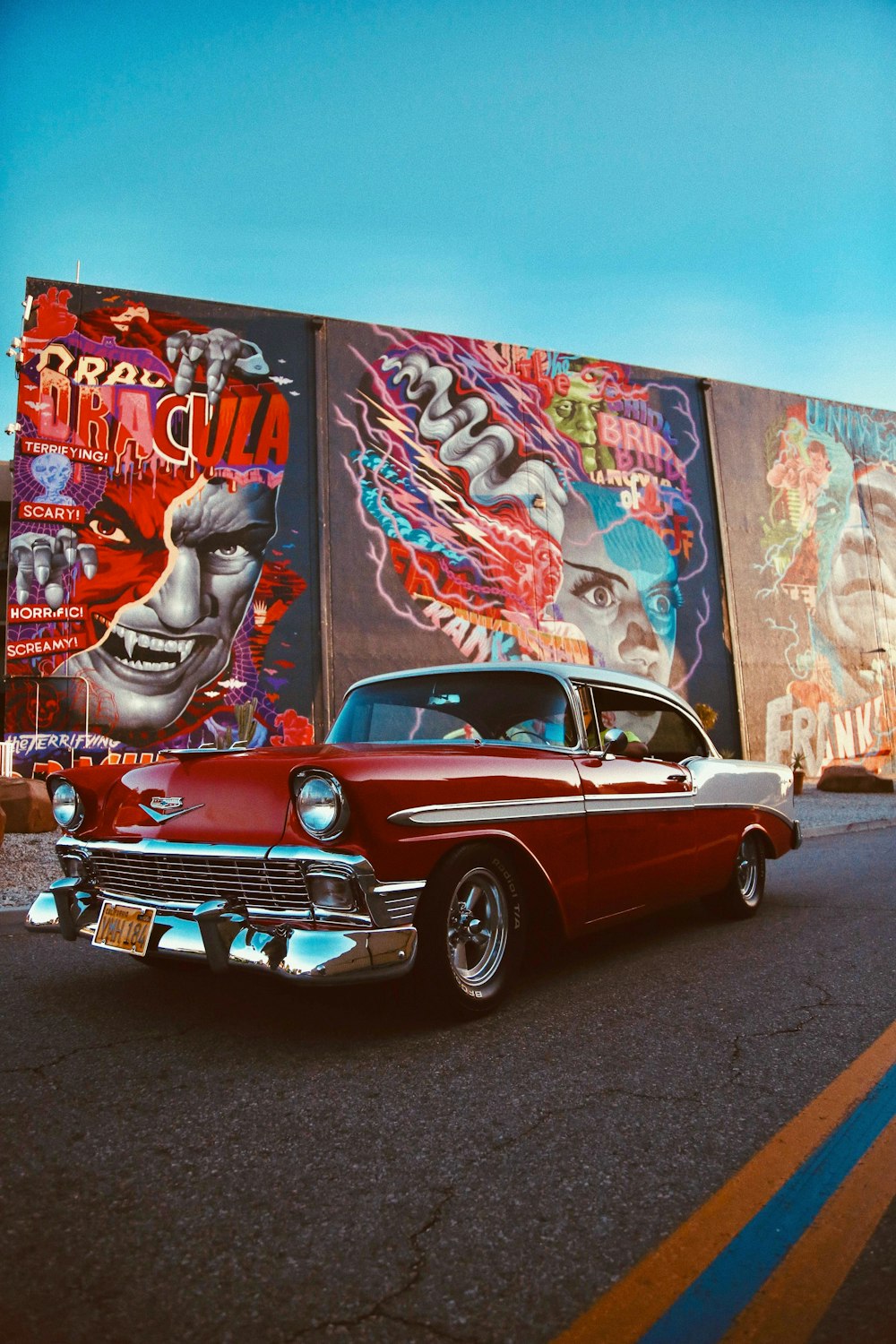 Voiture classique rouge garée à côté d’un mur avec des graffitis