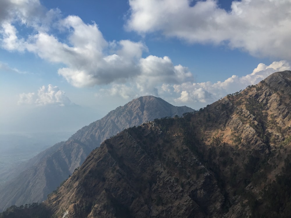 brown and green mountain under white clouds and blue sky during daytime