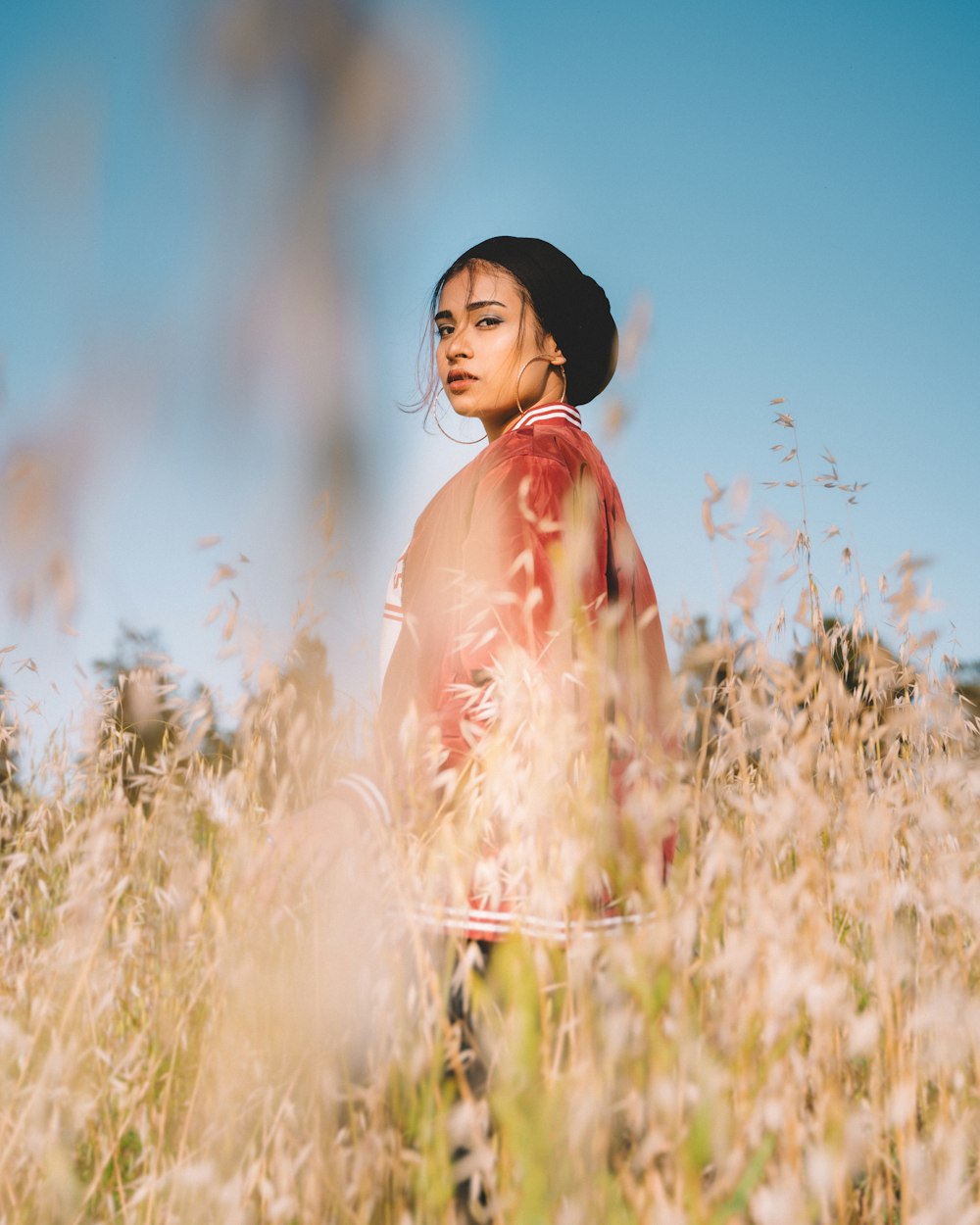 femme en robe rose debout sur le champ d’herbe brune pendant la journée