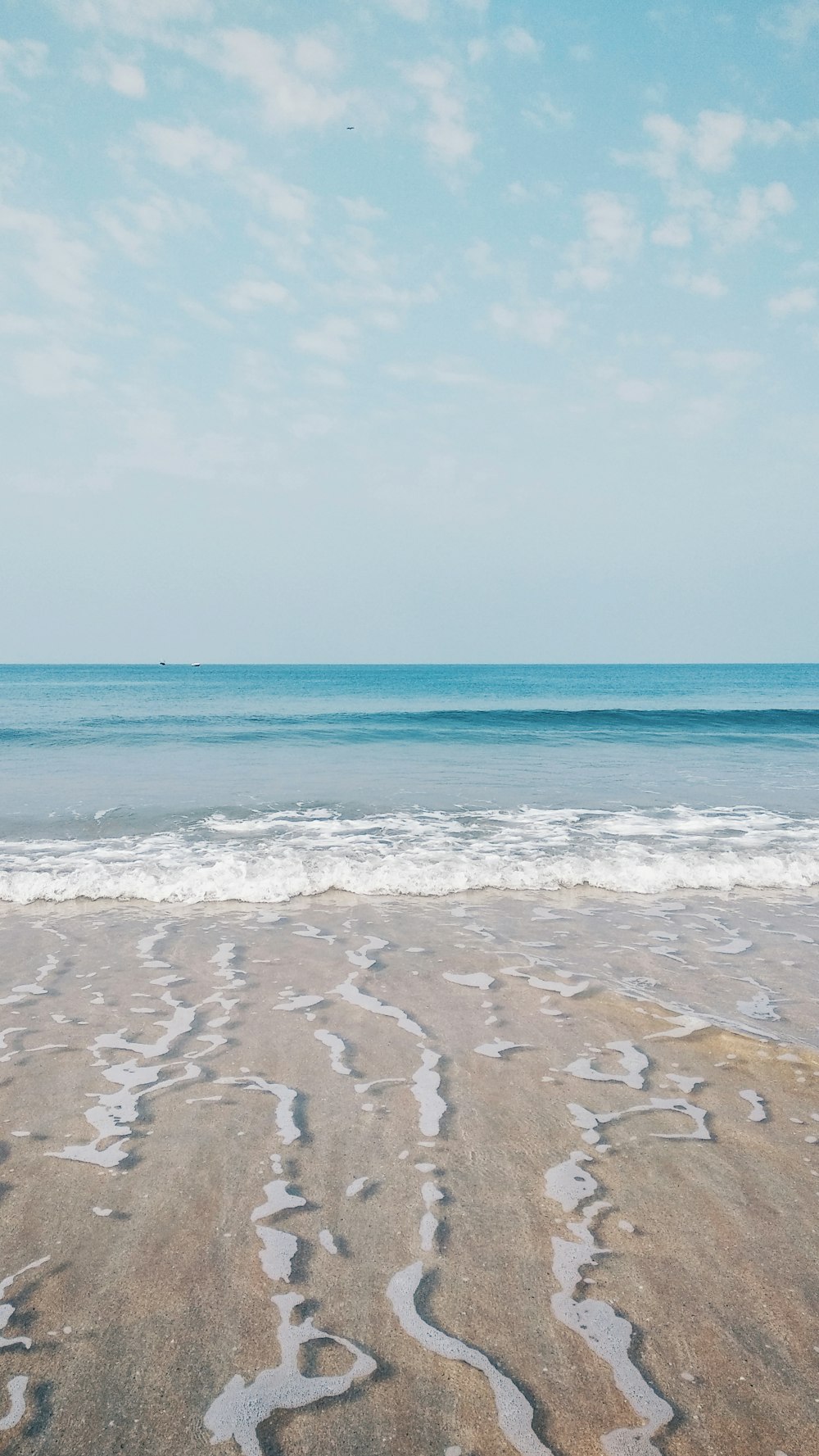 a sandy beach with waves coming in from the ocean