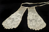 Close-up of a delicate lace mask with intricate floral patterns in soft cream tones.