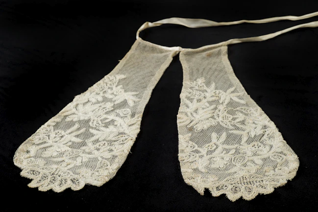 Close-up of a delicate lace mask with intricate floral patterns in soft cream tones.